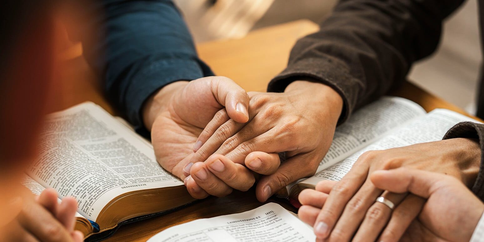 people-holding-hands-in-prayer-over-open-book-2026-01-09-07-38-43-utc